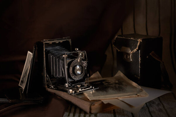 An old retro camera stands on the table with old photos                               