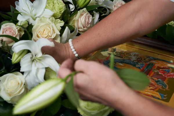 Hands of a woman florist, make a bouquet of white roses and lilies