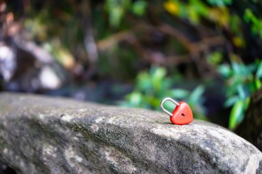 Kırmızı kalbin anahtarı arka planın olduğu taşın üzerinde.