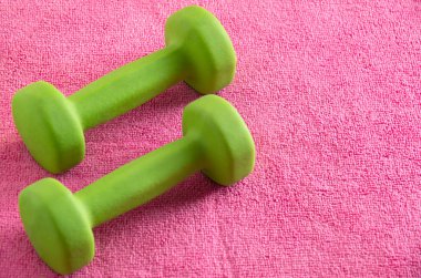 Pembe arka planda küçük yeşil Fitness dambıl