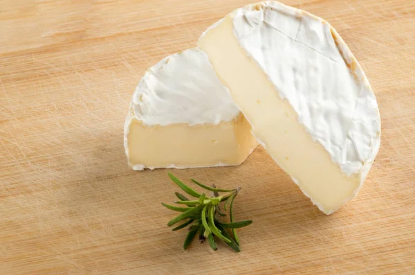 Camembert met stuk en groen op houten snijplank — Stockfoto