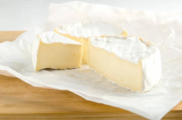 Camembert met stuk op wit inpakpapier — Stockfoto