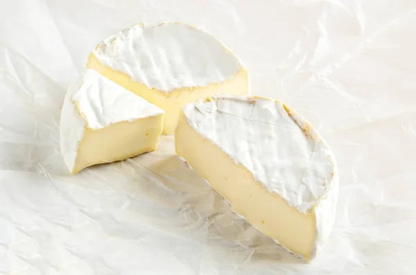 Camembert met stuk op wit inpakpapier — Stockfoto