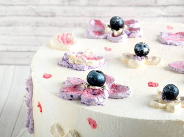 Beyaz süslemeli ev yapımı, ahşap arka planda yabanmersinli kek. Yakın plan.