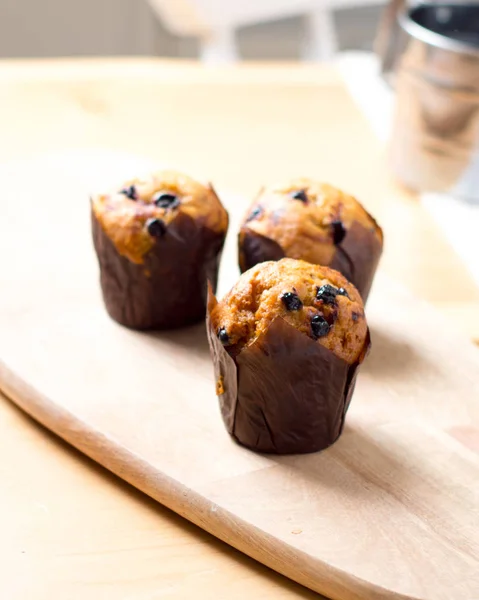 Muffins recém-assados com passas em tábua de madeira — Fotografia de Stock