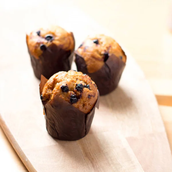 Muffins recém-assados com passas em tábua de madeira — Fotografia de Stock