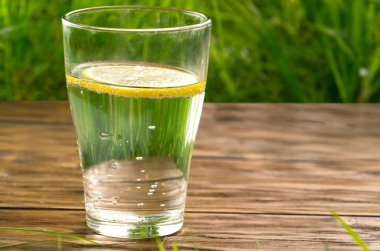 Taze yaz yeşil çim arka planda limon ile bir bardak su
