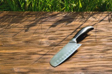 Bıçak eski ahşap yüzeyde yatıyor. Bıçak Santoku.