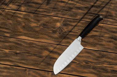 Bıçak eski ahşap yüzeyde yatıyor. Bıçak Santoku.