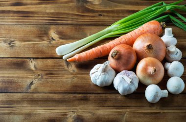 Ham soyulmamış soğan, yeşil soğan, champignons, sarımsak ve havuç ahşap koyu arka plan üzerinde