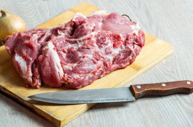 Ahşap tahta üzerinde çiğ et, soğan ve eski bıçak