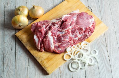 Ahşap tahtada çiğ et ve soğan halkaları