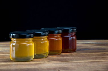 Ahşap masa üzerinde bal farklı renklerde küçük kavanozlar. Seçici odaklama.