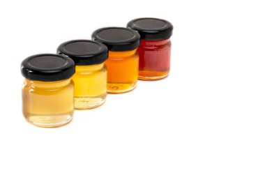 Beyaz arka planda bal farklı renklerde küçük kavanozlar