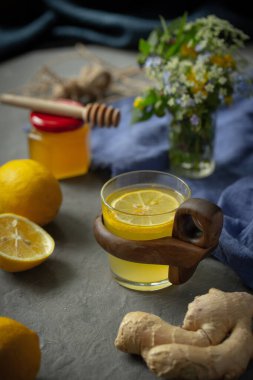 Zencefil, limon, bal ve çiçeklerin yanında çay ile şeffaf güzel bir kupa..