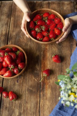 Bir çocuk ahşap bir masada oturur ve çilek yer..
