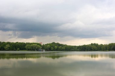 Parkın arka planında göl, yağmurlu bulutlar.