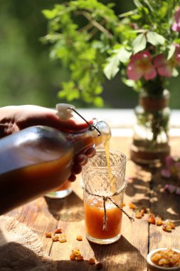Pencerenin yanında, bir adam bardaklara kvass döker..