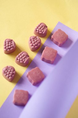Mor ve sarı arka planda çikolatalı şekerler. Fotoğraf için yer var. Reklam fotoğrafı.