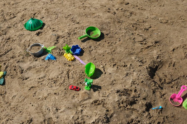 Children's toys are scattered on the sandy beach.