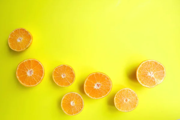 Orange still life. Fruit pattern of fresh orange slices on yellow background. Top view. Copy Space. Pop art design, creative summer concept. Half of citrus in minimal flat lay style. Banner