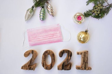 Beyaz arka planda, oyuncaklarla dolu bir Noel ağacı dalı. Noel arkaplanı. Cerrahi maske..