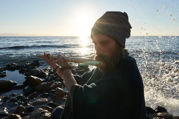 Игрок Bansuri играет музыку в лучах солнца на берегу моря . — стоковое фото