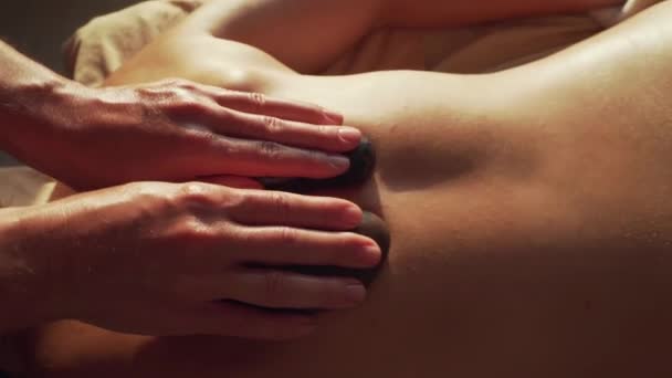 Primer plano de las manos femeninas haciendo masaje profesional de piedra caliente a la mujer joven — Vídeo de stock