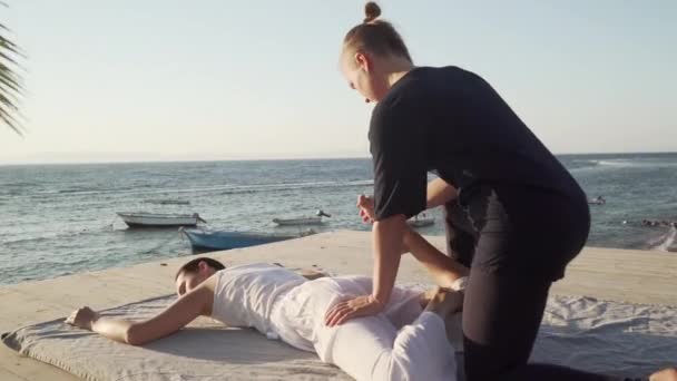 Stilig ung kvinna gör thai yoga massage på ett trägolv vid soluppgången — Stockvideo