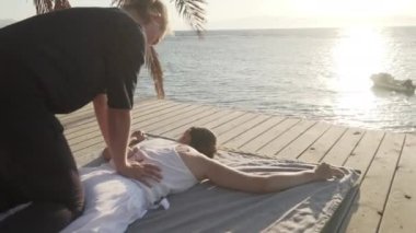 Tahta bir zeminde gün doğumunda Tayland yogası yapan çekici genç bir kadın.