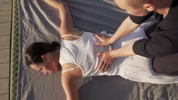 Вид зверху молода жінка робить тайський масаж йоги на дерев'яній підлозі на сході сонця — стокове відео