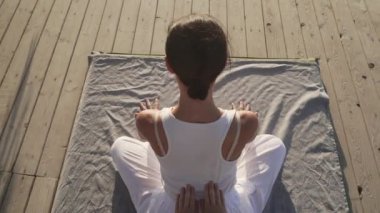 Güneş doğarken ahşap bir zeminde Tayland yogası yapan yakışıklı genç bayan.