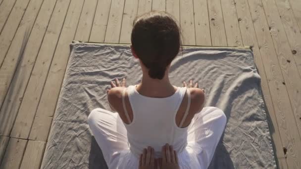 Красива молода жінка робить тайський масаж йоги на дерев'яній підлозі на сході сонця — стокове відео
