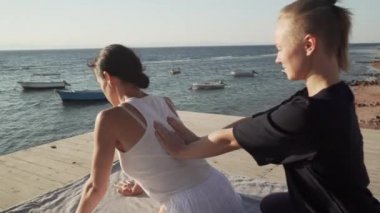 Genç bir kadın güneş doğarken ahşap bir zeminde Tayland yogası yapıyor.