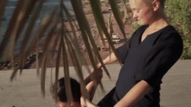 Genç bir kadın güneş doğarken ahşap bir zeminde Tayland yogası yapıyor.