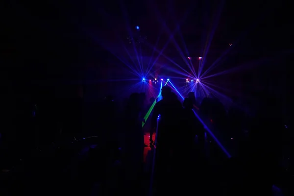 Multitud de personas bailando bajo la luz láser disco — Foto de Stock