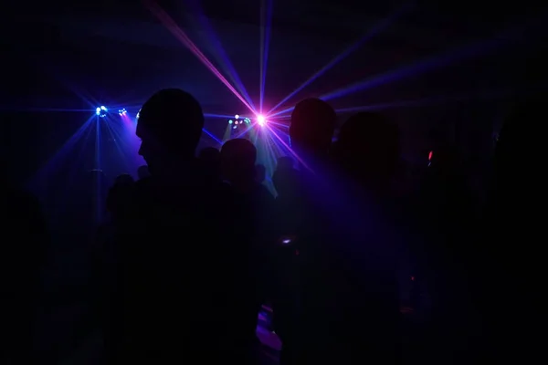 Menigte van mensen dansen onder disco laserlicht — Stockfoto