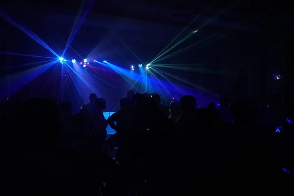 Multitud de personas bailando bajo la luz láser disco — Foto de Stock