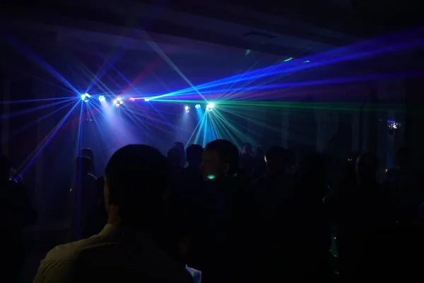 Multidão de pessoas dançando sob luz laser disco — Fotografia de Stock