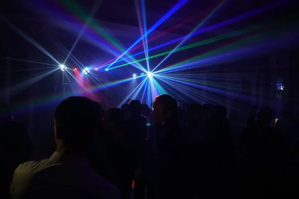 Folle di persone che ballano sotto la luce laser disco — Foto Stock