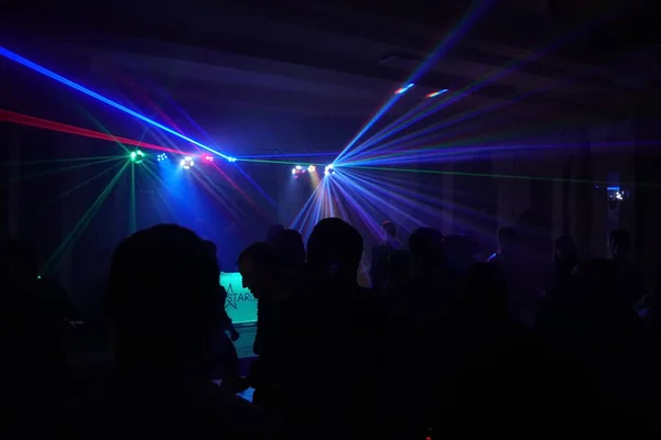 Multitud de personas bailando bajo la luz láser disco —  Fotos de Stock