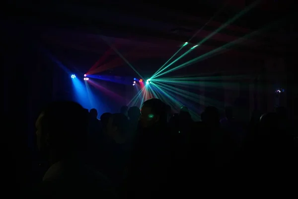 Multidão de pessoas dançando sob luz laser disco — Fotografia de Stock