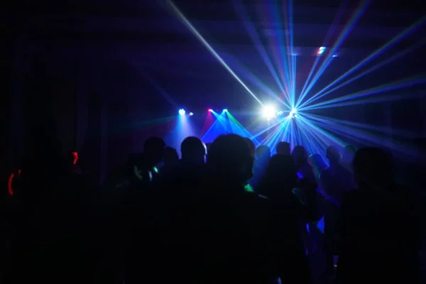 Multitud de personas bailando bajo la luz láser disco — Foto de Stock