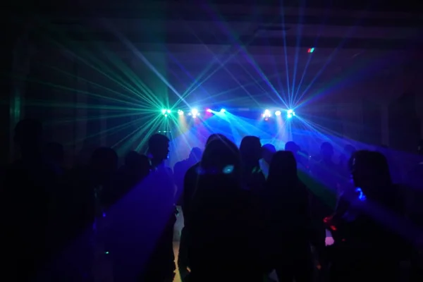 Menigte van mensen dansen onder disco laserlicht — Stockfoto