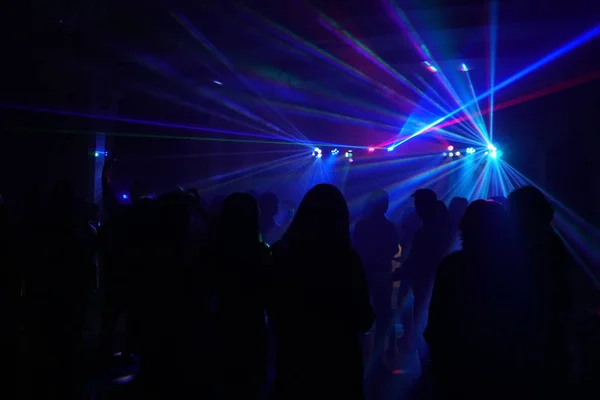 Menigte van mensen dansen onder disco laserlicht — Stockfoto