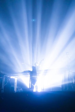 Parlak sahne ışıkları önünde konser kalabalığının siluetleri