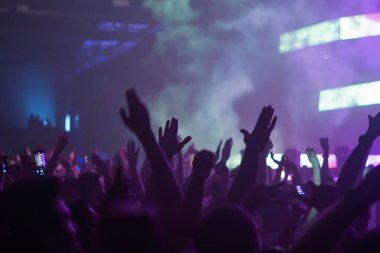 Konserin siluetleri parlak sahne ışıkları önünde kalabalık. Gece hayatı ve konser parti konsept.