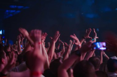 Konserin siluetleri parlak sahne ışıkları önünde kalabalık. Gece hayatı ve konser parti konsept.