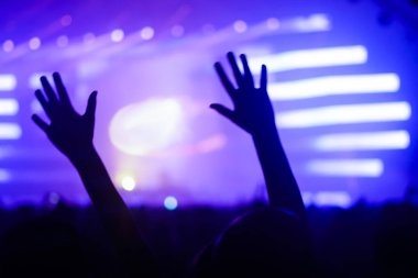 Konserin siluetleri parlak sahne ışıkları önünde kalabalık. Gece hayatı ve konser parti konsept.