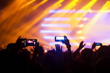 Konserin siluetleri parlak sahne ışıkları önünde kalabalık. Gece hayatı ve konser parti konsept.